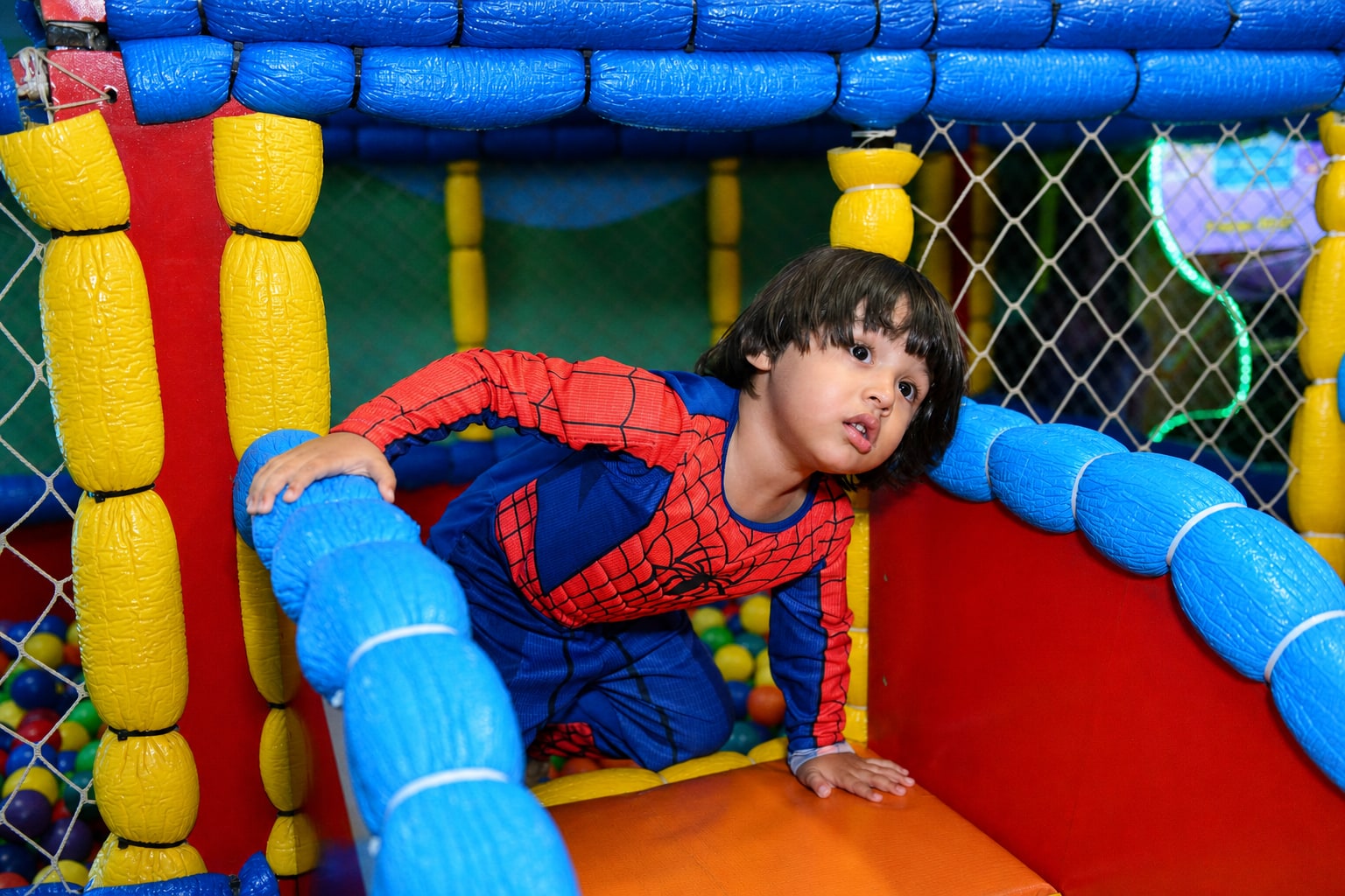 Criança fantasiada de Homem-Aranha brincando no playground do Niverlândia