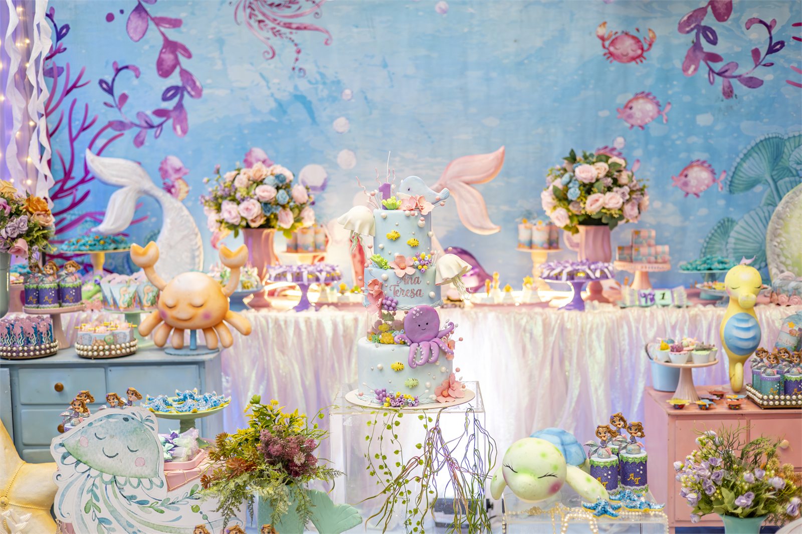 Mesa decorada de festa infantil com tema fundo do mar e bolo ao centro